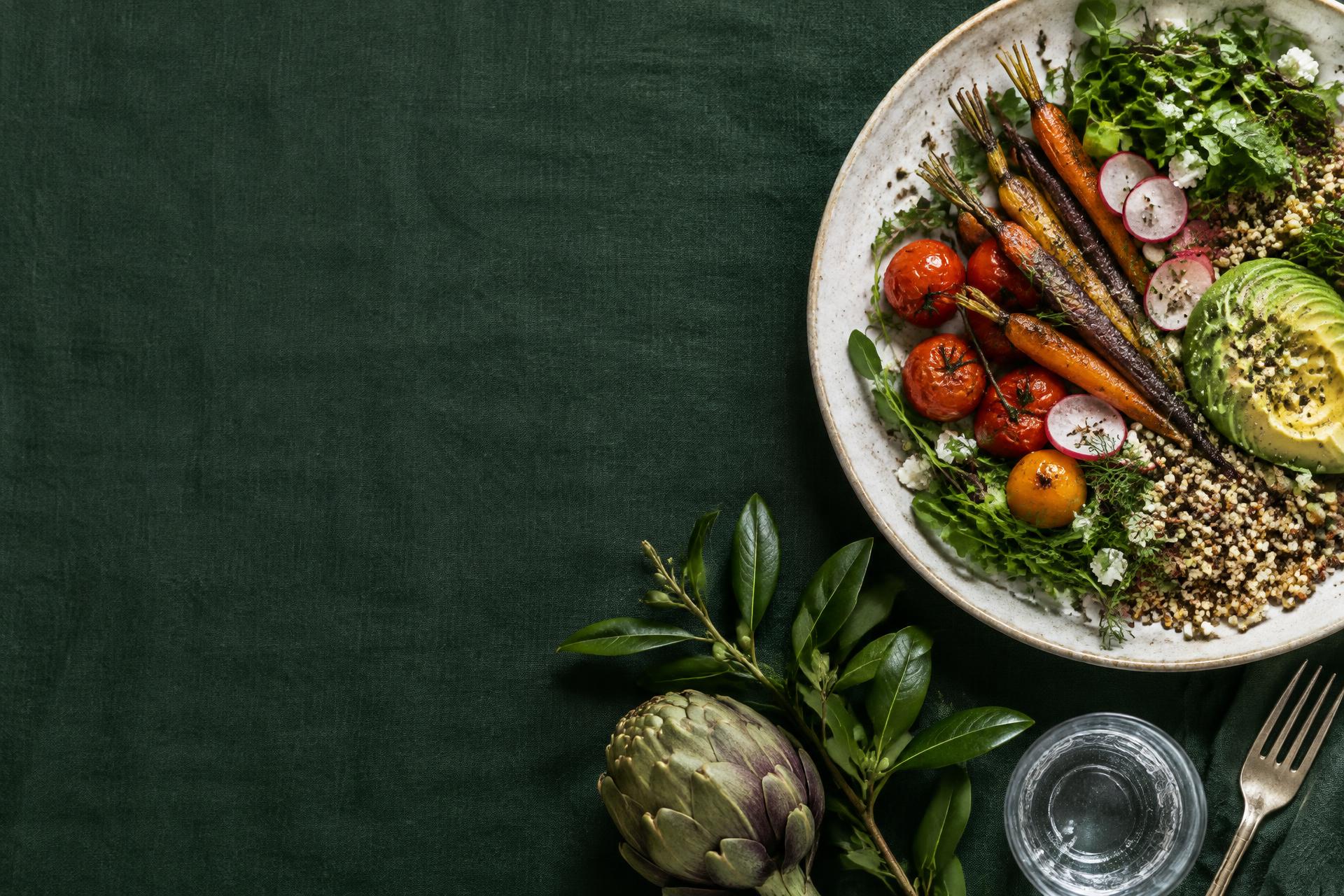 Plato de vegetales, quinoa y palta sobre una mesa verde